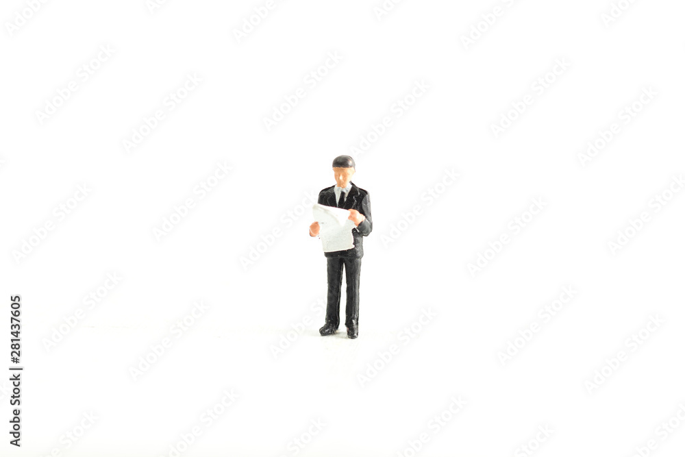 Miniature Businessman/Person Reading Newspaper/Documents on a White Isolated Background Miniature Businessman/Person Reading Newspaper/Documents on a White Isolated Background