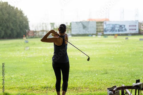 Asian woman practicing his golf swing at the golf driving range.
