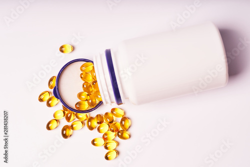 White bottle with scattered vitamins on white background