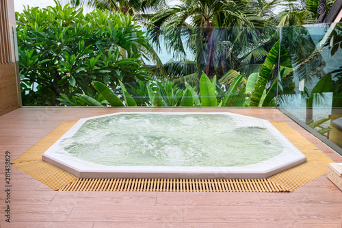Tablou pe pânză Luxury bathtub with water streaming installation on wooden patio with garden