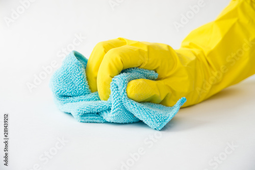 Closeup of a hand in a yellow latex glove using a blue towel to clean a counter top.