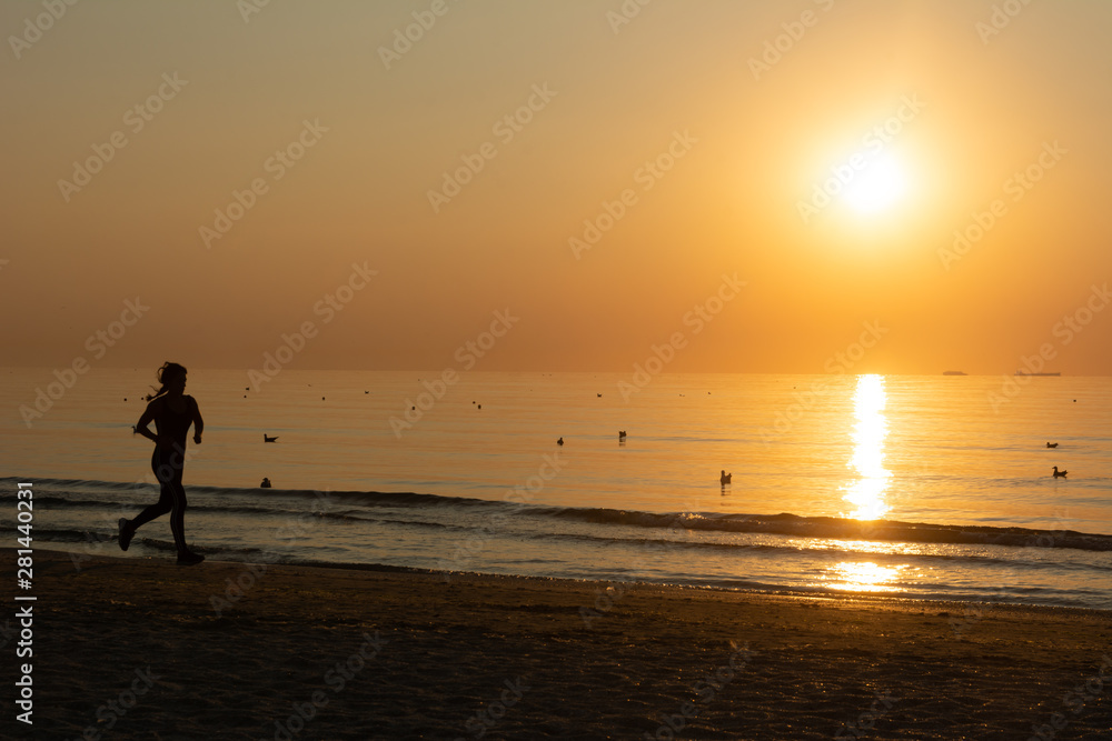 Woman running on the beach at sunrise