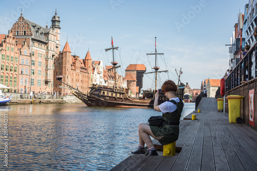 Canvas Print Young woman traveler near the river make photo of old buildings in the Gdansk