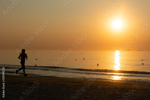 Woman running on the beach at sunrise