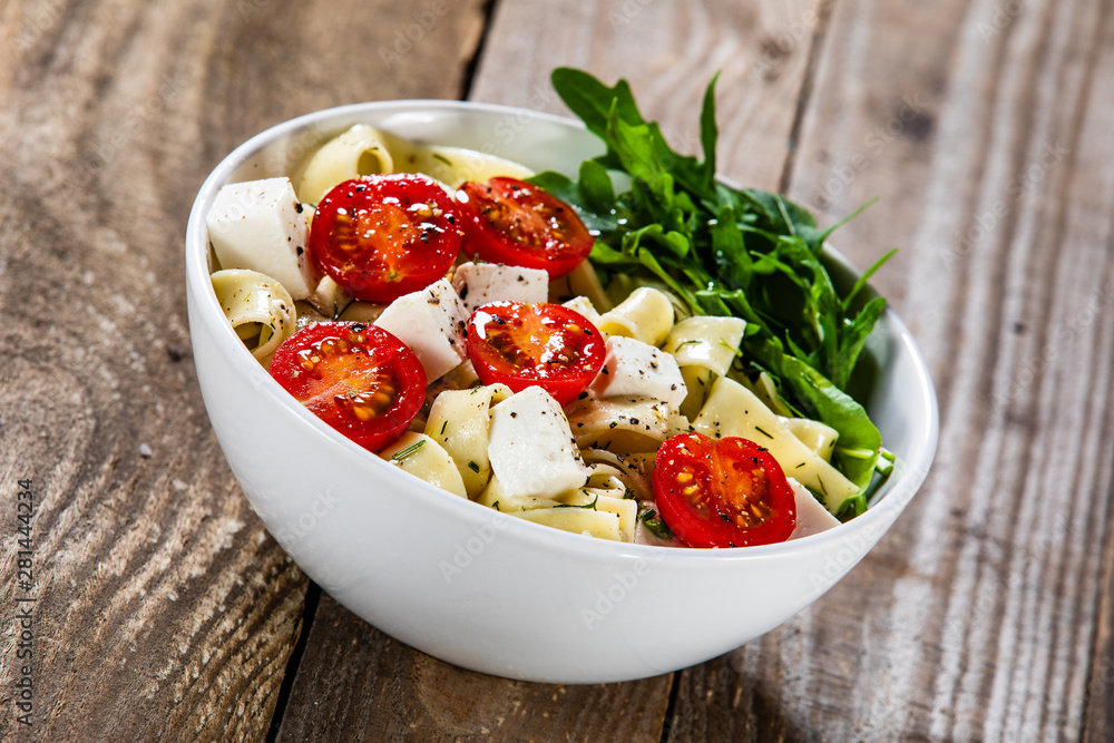 Pasta with tomatoes and white cheese on wooden table Pasta with tomatoes and white cheese on wooden table
