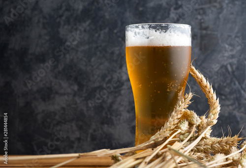 Misted glass of light beer on a wooden table and wheat photo