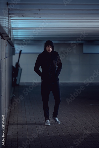 thief in black hoodie walking in underpass
