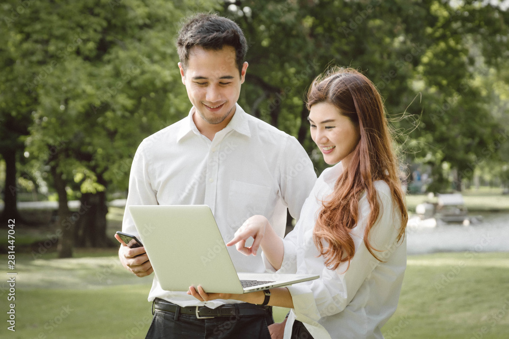 A man and woman couples using computer laptop and smartphone in the public park. A man and woman couples using computer laptop and smartphone in the public park.