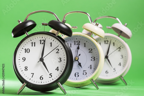 Black; yellow and white alarm clock against green background