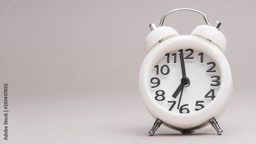 White small alarm clock against colored background White small alarm clock against colored background