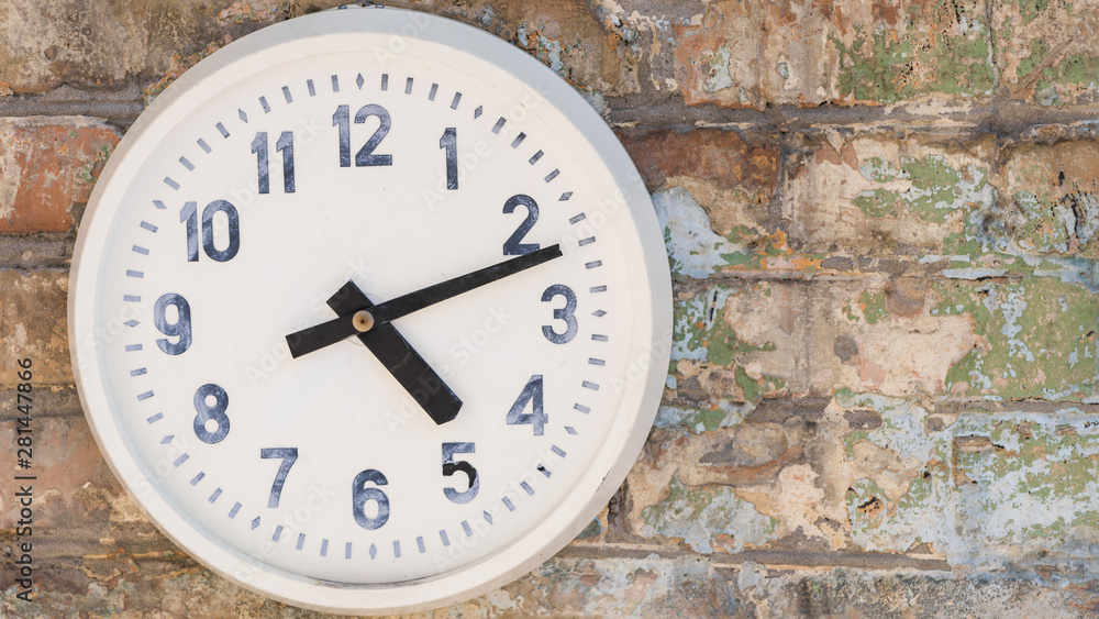 Round clock hanging on weathered brick wall