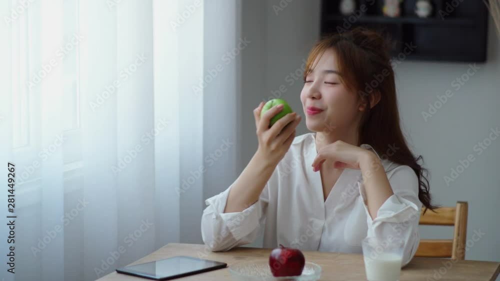 Beautiful woman thought with happily and eating green apple Beautiful woman thought with happily and eating green apple