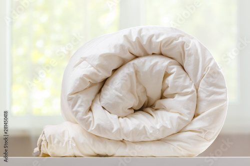 Fotografie A folded rolls duvet is lying on the dresser against the background of a blurred window