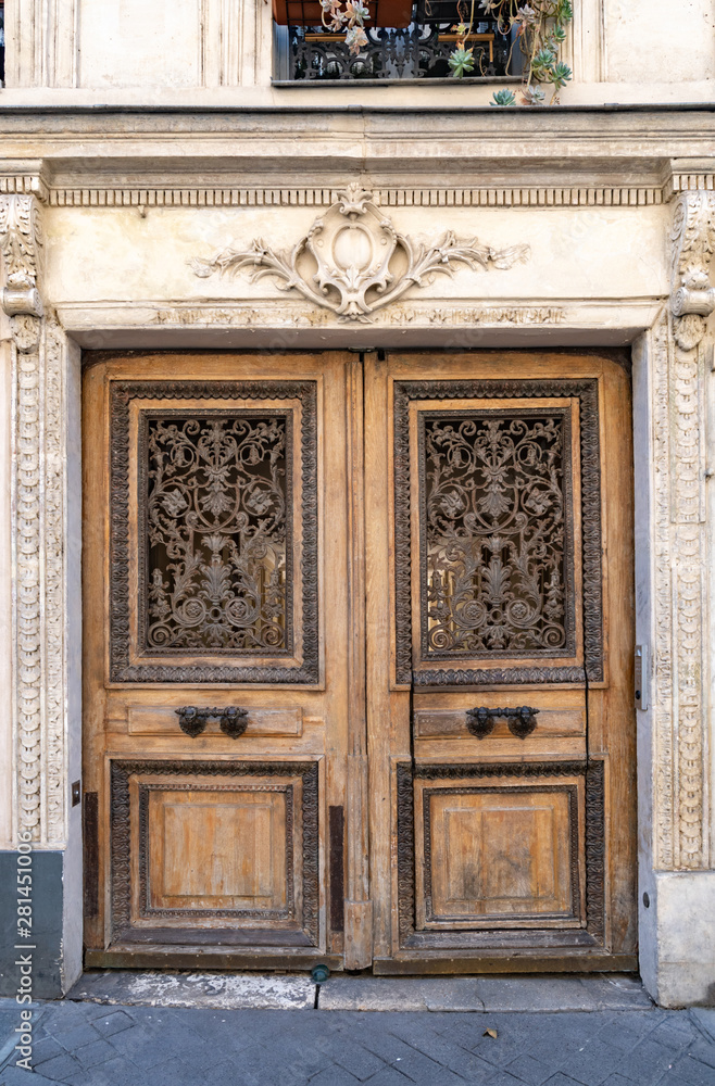Old wooden door. Aged double door entrance of old building in Paris France. Vintage wooden doorway and ornamental stucco fretwork wall of ancient stone house in classical architecture. Antique doorway