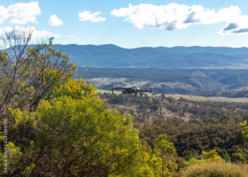 Fototapeta premium A small modern unmanned aerial vehicle drone in flight showing telegraph wires, landscape views and country scenery looking west of Canberra in the Australian Capital Territory