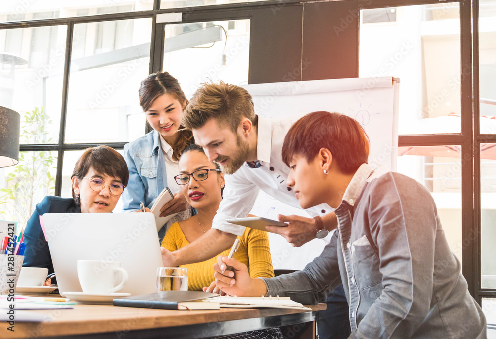Group of five casual business meeting to discuss ideas and laptop on table in office. Group of five casual business meeting to discuss ideas and laptop on table in office.