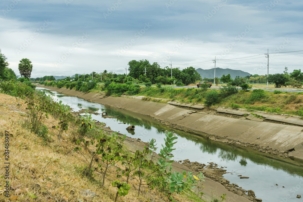 Fototapeta premium Irrigation canal in concrete wall Send water from the reservoir to the agricultural area of ​​the farmer that is dry in the rainy season of Thailand. Environmental disaster in agriculture