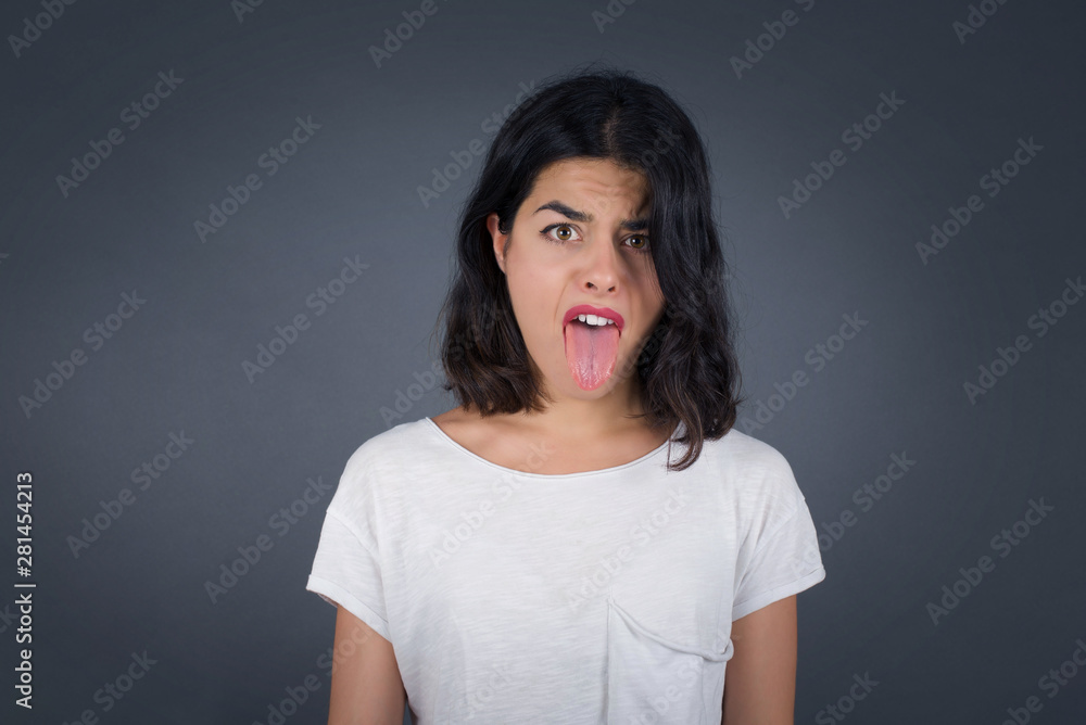 Body language. Disgusted stressed out pretty girl with straight fair hair posing against gray wall, frowning her face, demonstrating aversion to something. Body language. Disgusted stressed out pretty girl with straight fair hair posing against gray wall, frowning her face, demonstrating aversion to something.