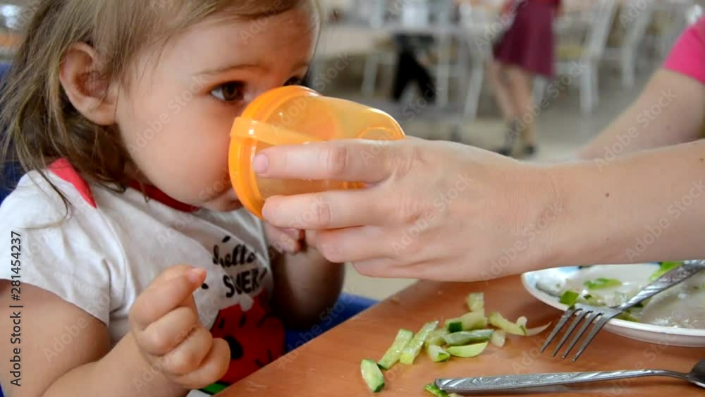 childhood and people concept - little baby drinking from spout cup ...