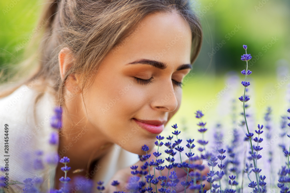 gardening and people concept - close up of happy young woman smelling lavender flowers at summer garden - obrazy, fototapety, plakaty 