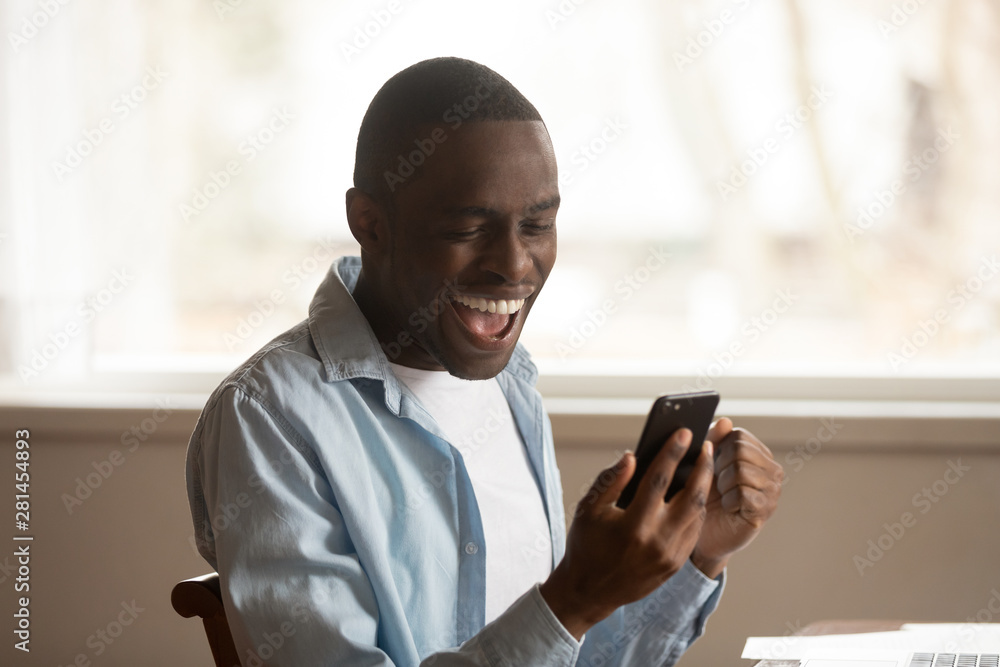African guy look at cellphone read great news feels happy African guy look at cellphone read great news feels happy