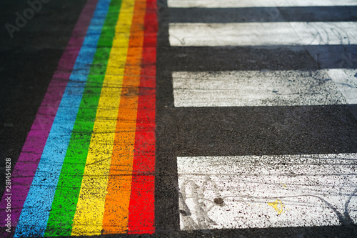 Road marking of pedestrian crossing and rainbow flag in Paris. Sex discrimination concept. Selective focus. The symbol of the LGBT community, equal rights