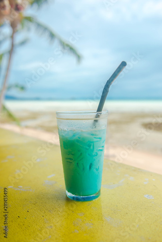 Icy blue milk shake on yellow table.
