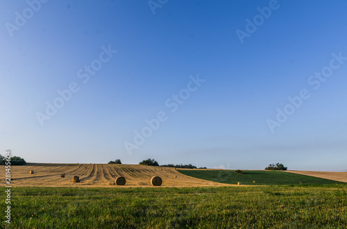 Landscape photo with blue sky, mowed field and hay bales