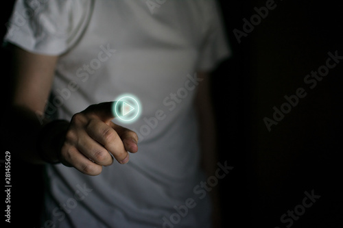 Hand of a man pressing the "play" button on black background