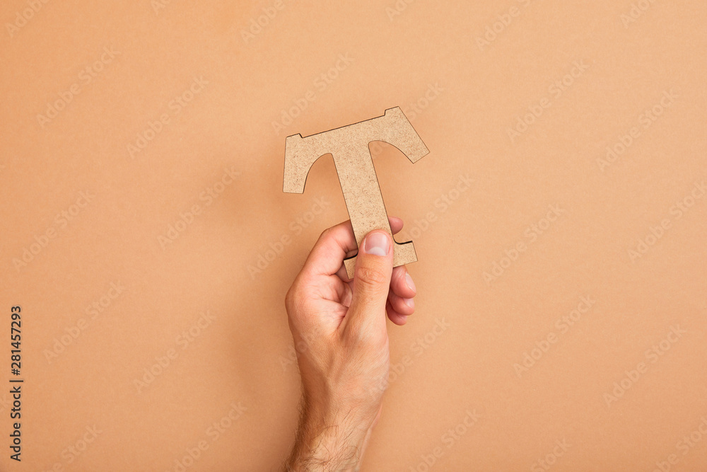 partial view of man holding paper cut letter T on beige background partial view of man holding paper cut letter T on beige background