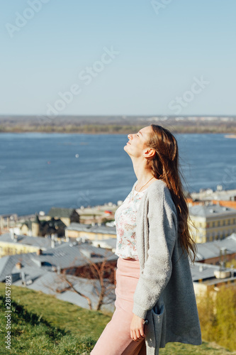 Young beautiful brunette girl walking along the river in Europe. Woman tourist travels to the cities of Europe.