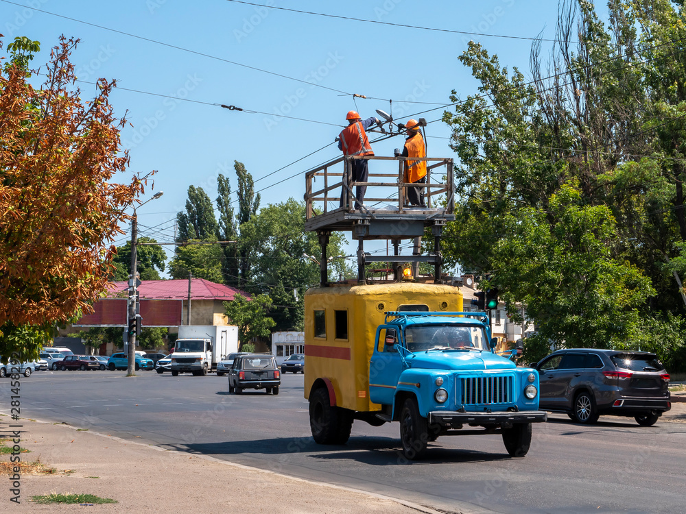 Emergency vehicle on the road. Workers paint trolley wires, stand on the tower. Painting works. Maintenance of the contact network. Repairs. Public utilities