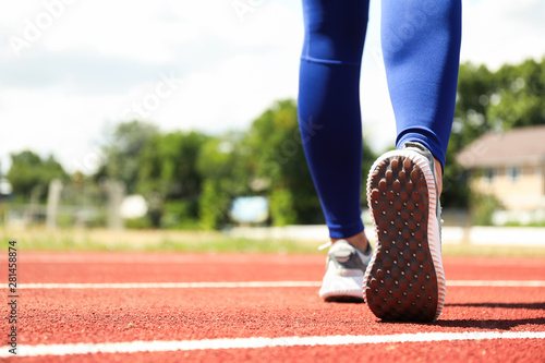 Girl walking on red athletic track, space for text