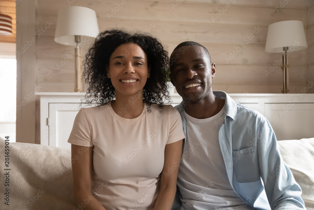 Obraz premium Smiling african couple sitting on couch making video call