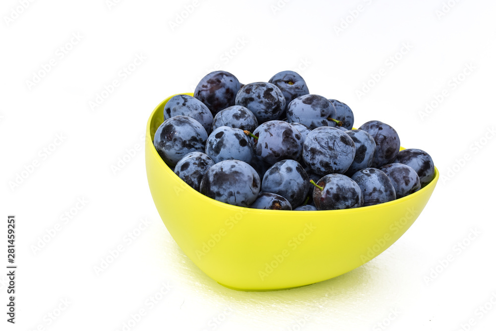 Ripe plums in the yellow bowl with white background. The summer harvest. Ripe plums in the yellow bowl with white background. The summer harvest.