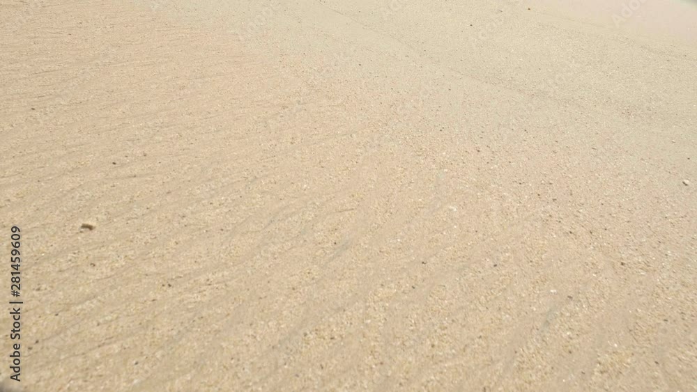 A hanheld shot of tropical beach sand with footprints A hanheld shot of tropical beach sand with footprints