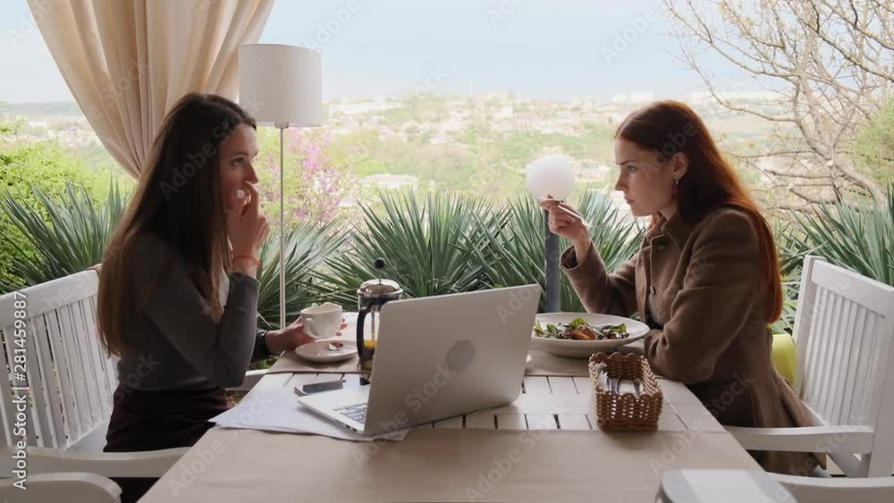 Two girls discuss their work things eating salads and drinking tea slow motion
