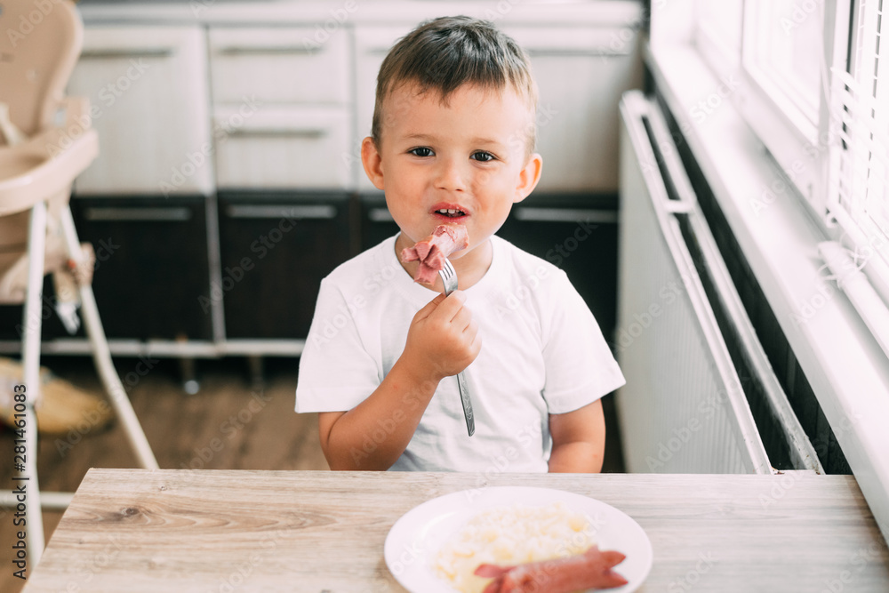 child in the kitchen eating sausage and mashed potatoes child in the kitchen eating sausage and mashed potatoes