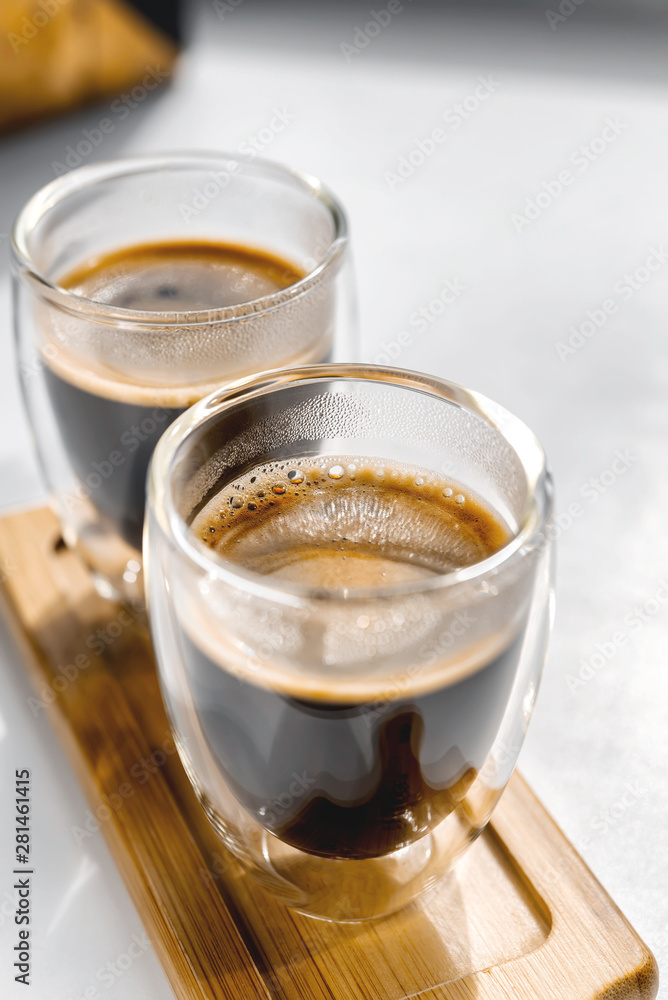 Two cups of fresh espresso on a wooden tray, on a white background. Sunlight from the window Two cups of fresh espresso on a wooden tray, on a white background. Sunlight from the window