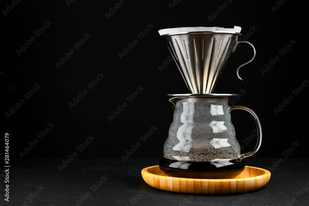 Alternative coffee brewing method,pure over,glass teapot on wooden tray with freshly brewed coffee on dark background. Alternative coffee brewing method,pure over,glass teapot on wooden tray with freshly brewed coffee on dark background.