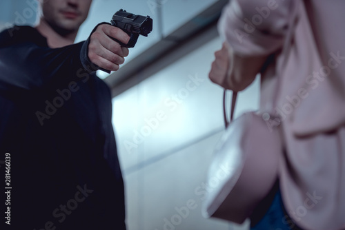 Bild auf Leinwand cropped view of robber pointing gun at woman