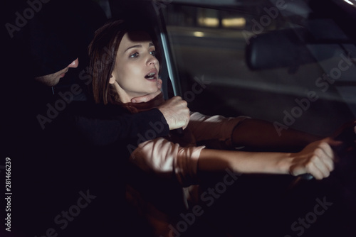 thief strangling beautiful frightened woman in automobile at night