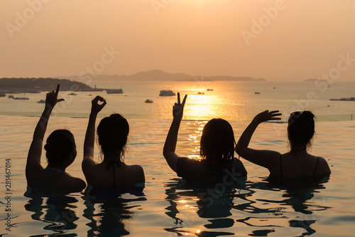 Silhouette of ladies show LOVE hands in a pool by the ocean