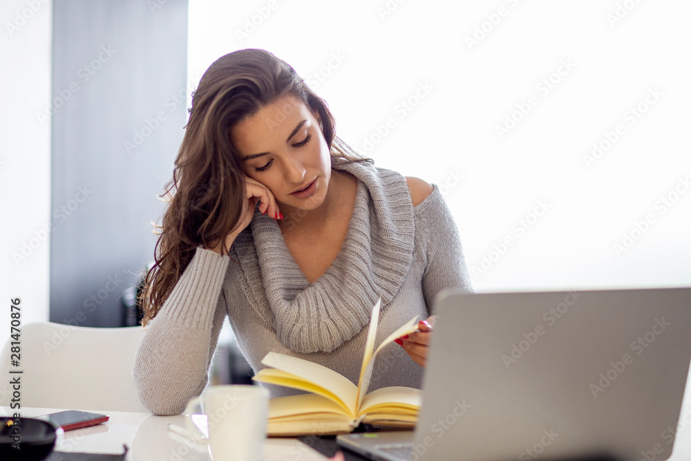 Beautiful woman sitting with laptop and coffee mug and note book on the table Beautiful woman sitting with laptop and coffee mug and note book on the table