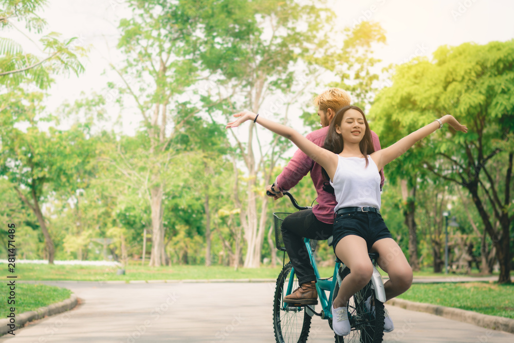 Fototapeta premium Young couple going for a bike ride on a sunny day in the park, love, relationship, romance concept.