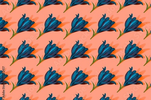 Blue lilies on orange background trend flat lay concept with fashionable toning. Many flowers pattern