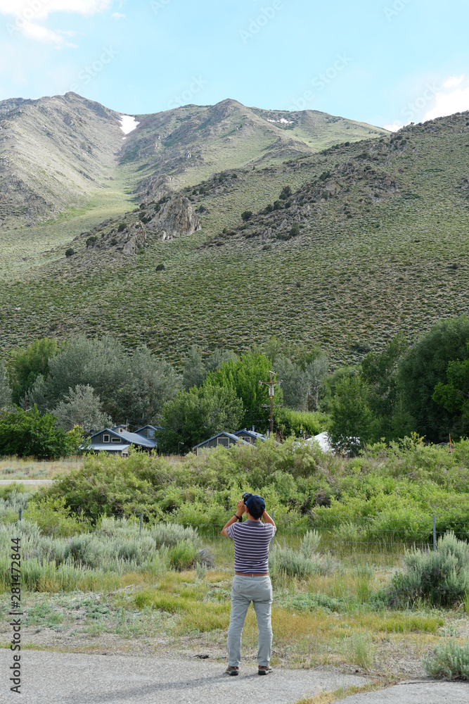 Asian man visiting and taking photo of the Sierra Nevada range mountain, Mono County, California. USA.
