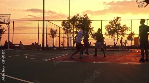 Sunset Basketball Game captures a group of young men playing basketball at sunset, creating a silhouette look.                                                                                          
