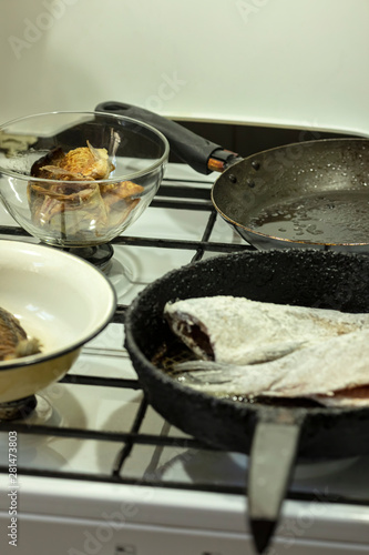 Pieces of river fish are fried in a pan on the stove. Cooking at home.