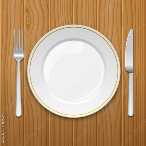Empty plate with fork and knife on wooden table